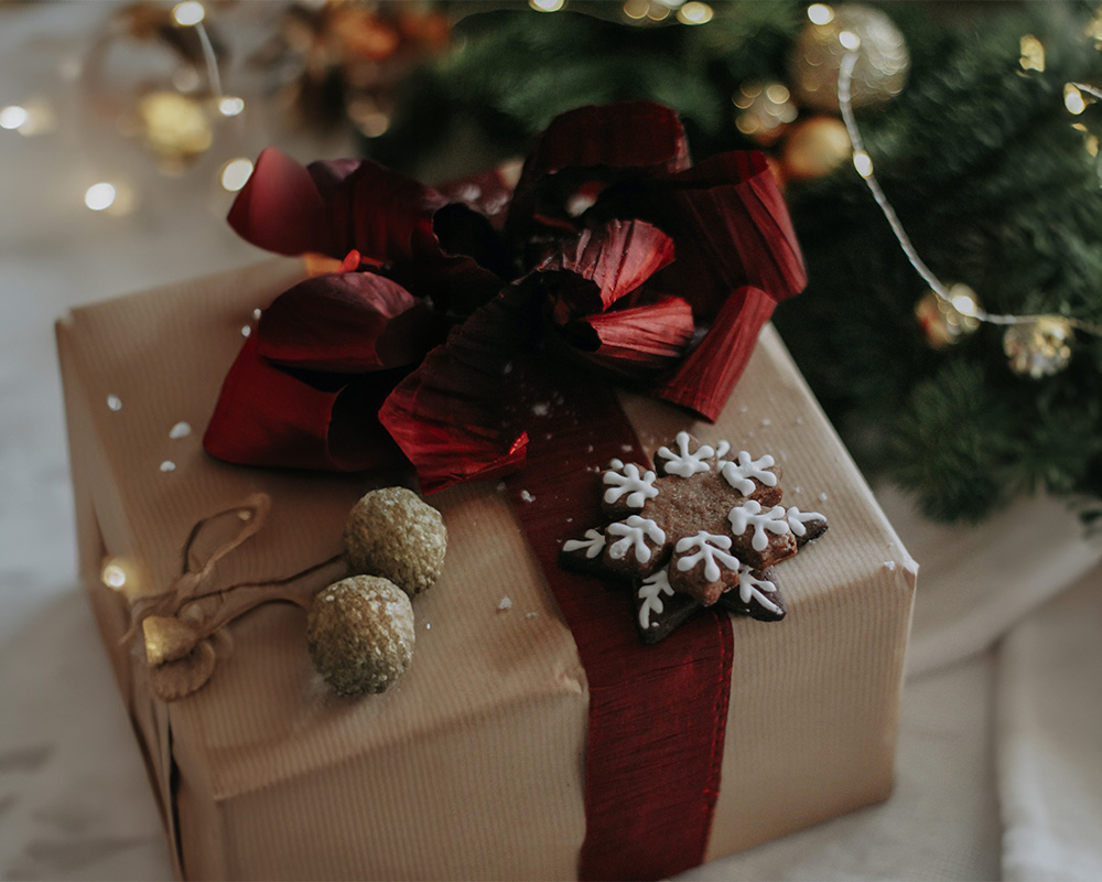 Prenda de Natal embrulhada em papel, atada com um laço e decorada com um biscoito.