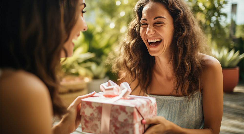 Mulher sorridente oferece uma prenda a um amigo.